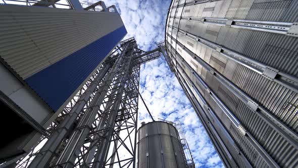 Metal construction on a modern industrial plant. Large grain elevators on beautiful sky background. 