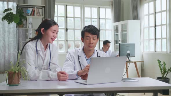 Asian Professional Physicians Talking, Consulting And Working On Laptop Computer