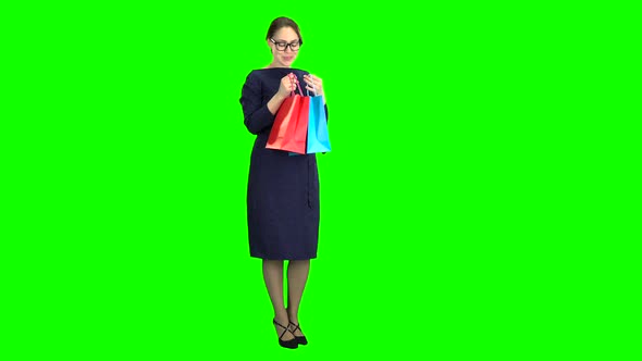 Girl Looks in the Shopping Bags and Rejoices. Green Screen