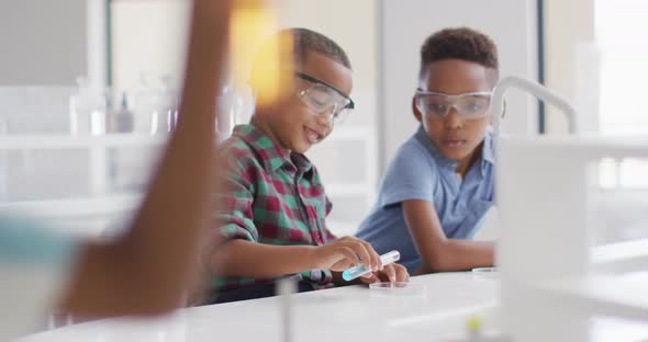 Video of happy african american boys wearing glasses during chemistry lesson