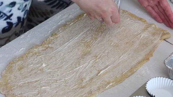 A Woman Sprinkles Stuffing Onto Rolled Out Dough For Kruffin.