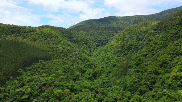 Aerial drone view of a green valley with hills and dense forest.