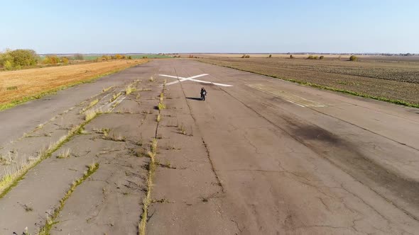 A Motorcycle with Riders of a Man and a Woman Rides at Speed on the Old Runway