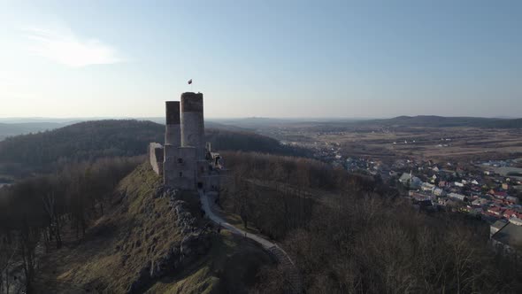 A rearward aerial drone shot of the Chęciny Royal Castle from its side entrance with footpath. This