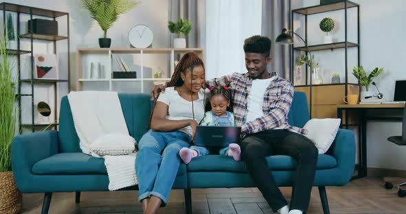 African Couple with Daughter Using Laptop at Home