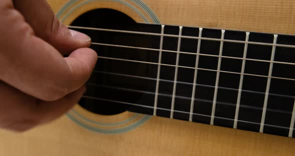 Closeup of Male Musicians and Playing the Strings of an Acoustic Guitar