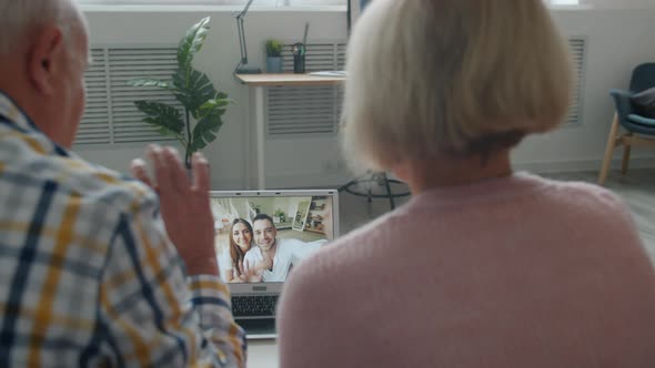 Back View of Senior Couple Making Online Video Call with Laptop From Home