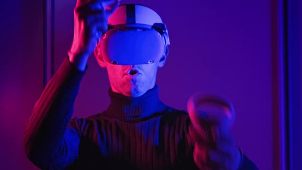 Young Man in VR Helmet Interacts with Virtual Reality Using Controllers