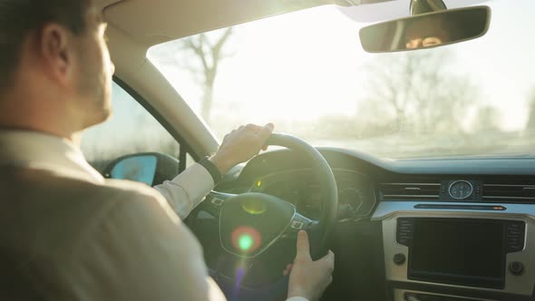 Rear View to Young Man Drives a Car