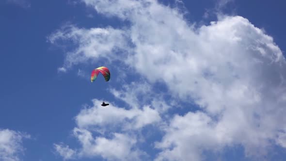 Paraglider on Blue Sky Background and Clouds