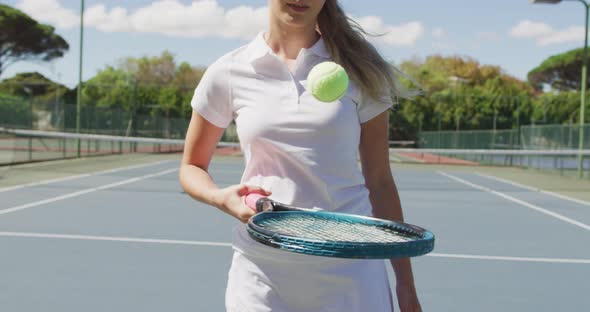 Video of midsection of caucasian female tennis player holding racket and bouncing ball
