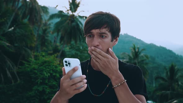 Shocked Young Man Traveler Using Smartphone Loses Dissatisfied with Bad News Outdoors