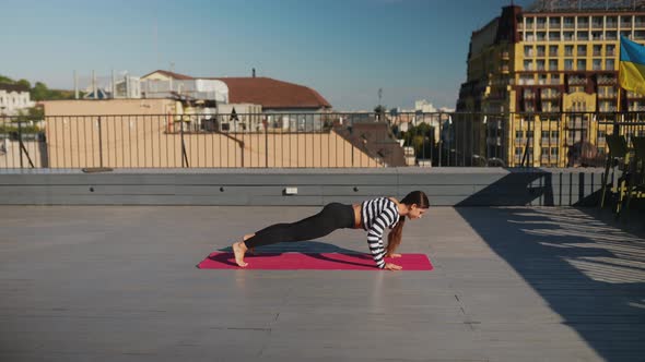 Woman Doing Yoga Exercises on House Roof in Early Morning