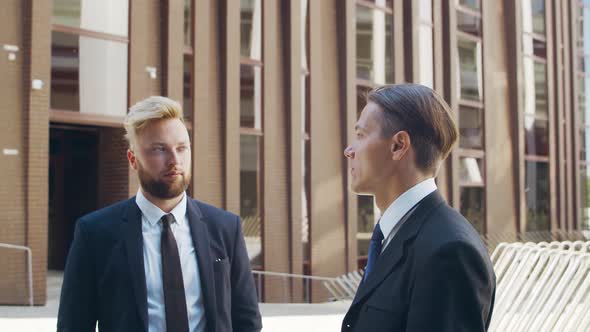 Confident businessman and his colleague in front of modern office building.