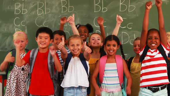 Smiling kids showing thumbs up in classroom