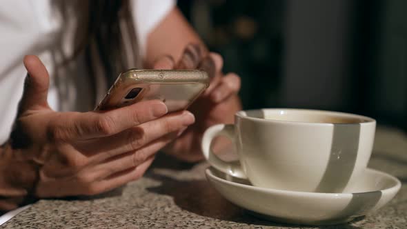 Woman is Surfing Internet and Viewing Social Networking By Cellphone in Cafe Closeup of Hands