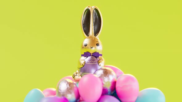 Cute chocolate bunny sitting on top of the pile of delicious glittering eggs.