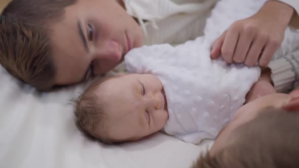 Cute Infant Sister Lying in Bed with Brothers Touching Caressing Little Baby in Slow Motion