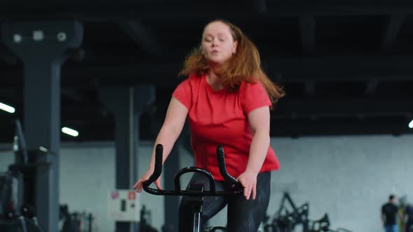 Athletic Woman Riding on Spinning Stationary Bike Training Routine in Gym Weight Loss Indoors