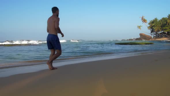 Professional Athlete Runs Along Sandy Beach in Summer