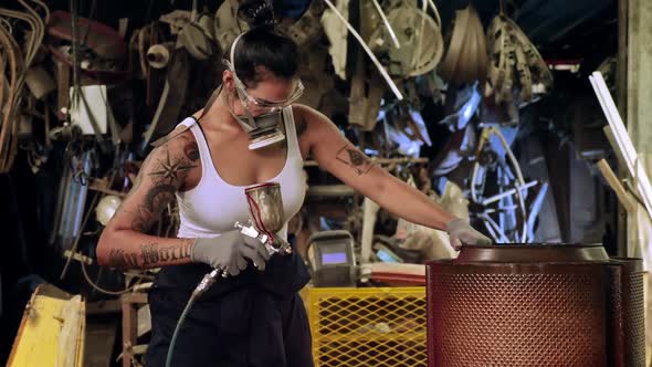 Attractive young woman mechanical worker repairing a vintage car in old garage.