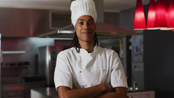 Mixed race male chef standing in kitchen looking at camera and smiling