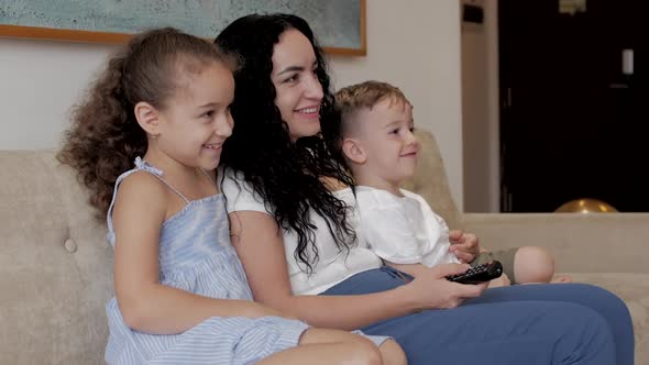 Happy Family, Mom and Cute Little Children Watch the TV, Mom Plays with Children at Home, Relaxing