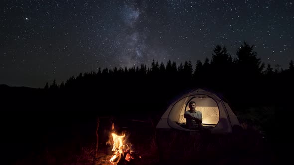 A Man Rests in a Tent Near at Night