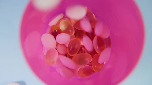 Pink and Yellow Tablets Fall Into a Plastic