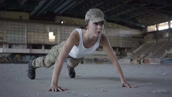 Young Woman in Military Uniform Wrings Out From the Floor on a Concrete Floor