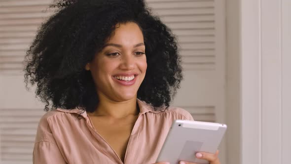 Cute African American Woman Browses Content or Communicates on Social Networks Using Digital Tablet