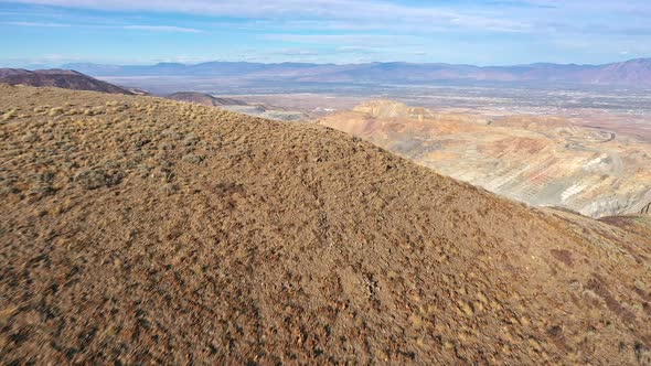 Flying over mountain top revealing Bingham Copper Mine in Utah