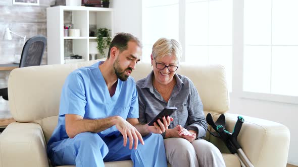 Male Doctor Teaching Senior Woman How To Use Her Phone