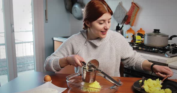 Girl is Mashing Boiled Potatoes for the Preparation of Dumplings and Croquettes