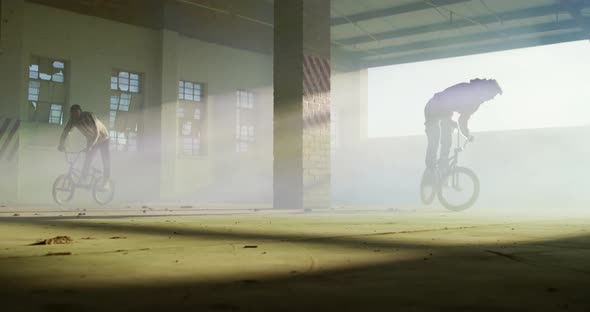 BMX rider in an empty warehouse using smoke grenade