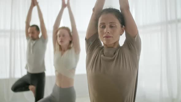 Yoga Class Group of Three Women and Man Exercising Healthy Lifestyle in In Bright Studio