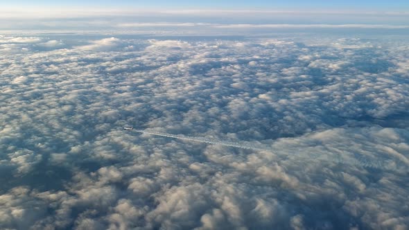 Incredible view from the cockpit of an airplane flying high above the clouds leaving a long white co