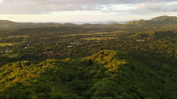 Aerial footage of beautiful hilly landscape dominated by rainforest with few small houses within. Re
