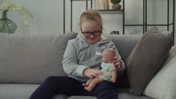 Joyful Child with Down Syndrome Hugging Doll on Sofa