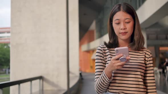 A woman wearing neat clothes uses a mobile phone to send messages and chat online.