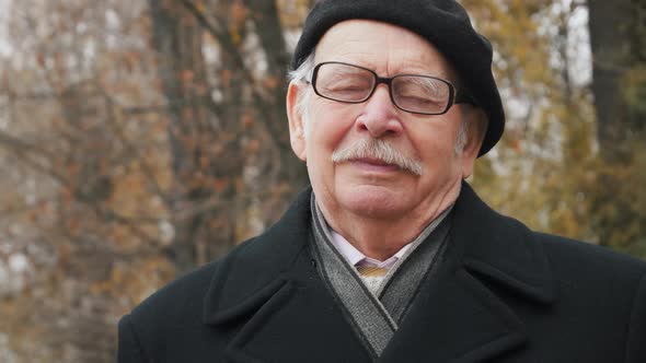 Portrait of old senior Wearing in a black hat and coat and Exhaling Fresh Air, Taking Deep Breath, R