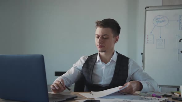 Business Man Working on Laptop Computer and Writing on a Paper with Pen