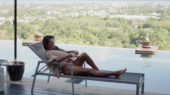 Woman Lying on Deckchair on Top of Hotel Pool Terrace