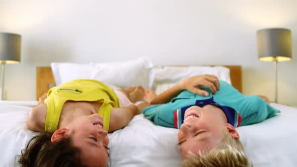 Siblings relaxing on bed in bedroom