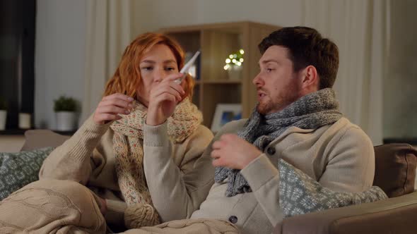 Sick Couple with Thermometer and Tea at Home