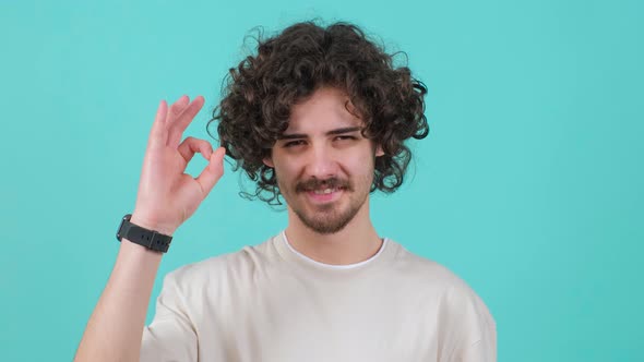 Close Up of a Positive Curly Haired Young Man Showing Ok Gesture with Fingers