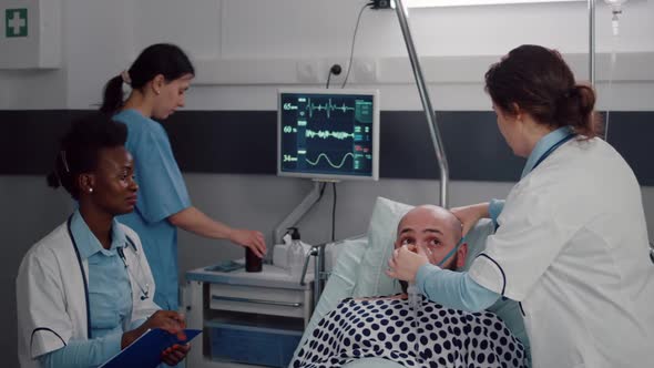 Sick Man Resting in Bed While Woman Medic Putting Oxygen Mask