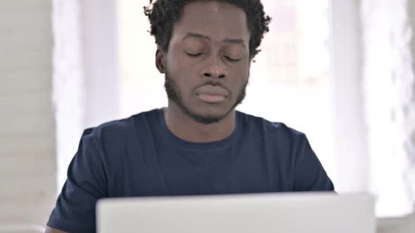 Close Up of Tired African Man Rubbing Eyes in Office