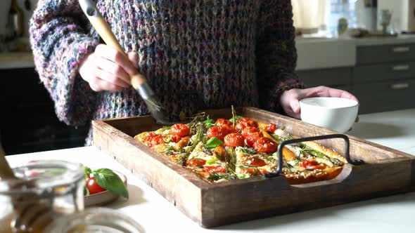 woman prepares focaccia with whole carrots and asparagus