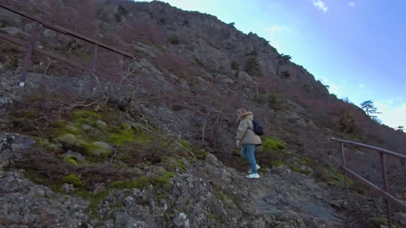 Woman Hiker with Backpack and Her Dog Walking on Hill Slope